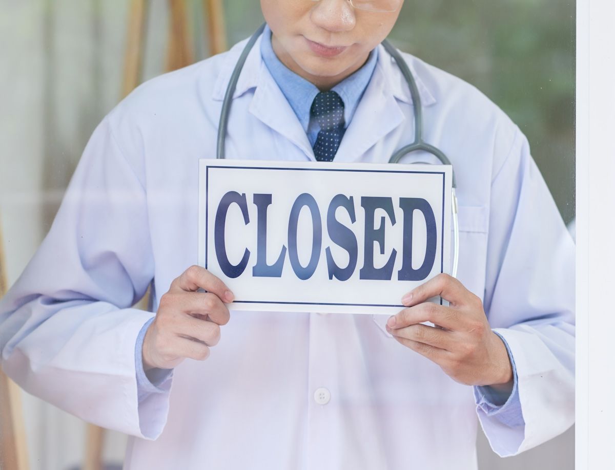 doctor physician holding closed sign: © DragonImages - stock.adobe.com