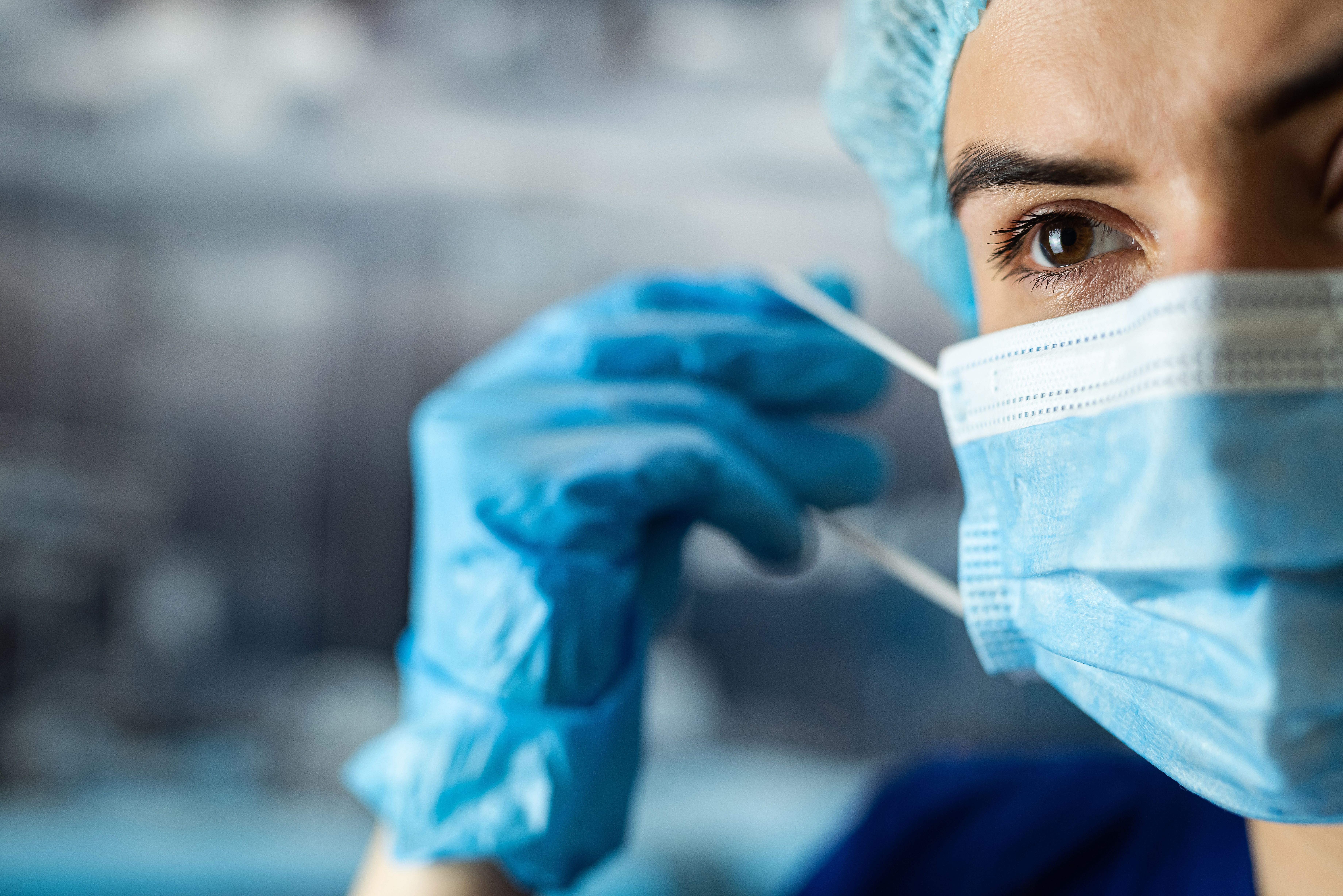 Health care professional putting on a face mask -- Image credit: RomanR | stock.adobe.com
