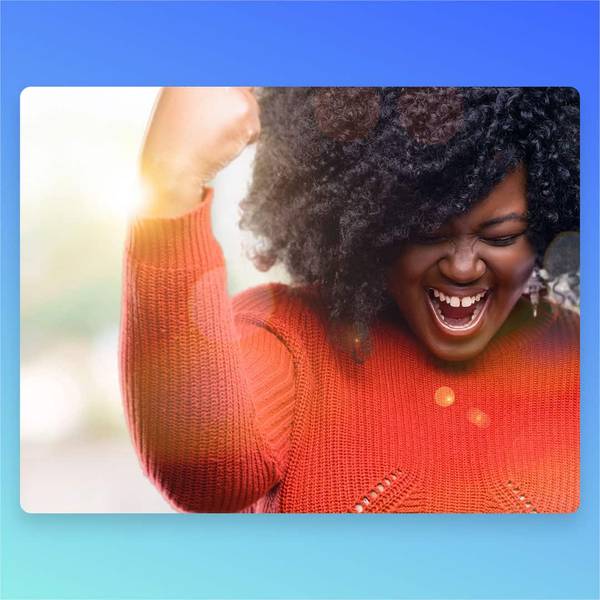 Excited woman in orange sweater celebrating with fist raised and joyful expression outdoors