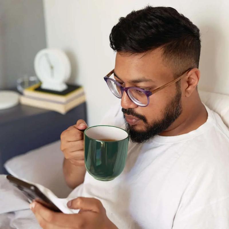 Man Drinking Coffee Looking at Phone