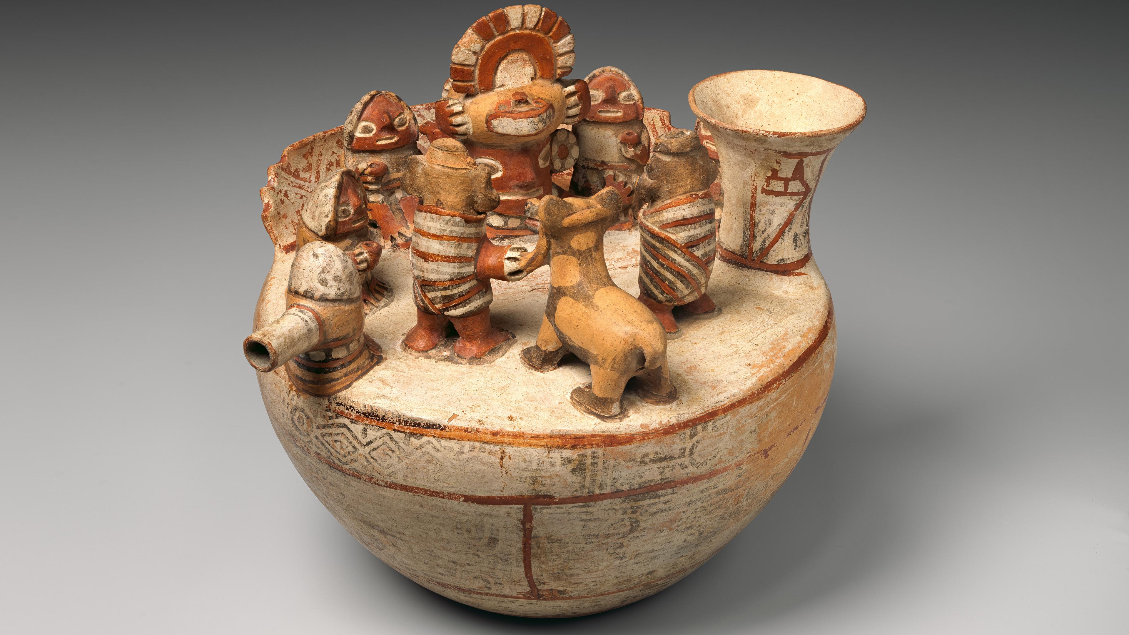 A red and white ceramic vessel with sculptural figures on the deck arranged in a ritual scene