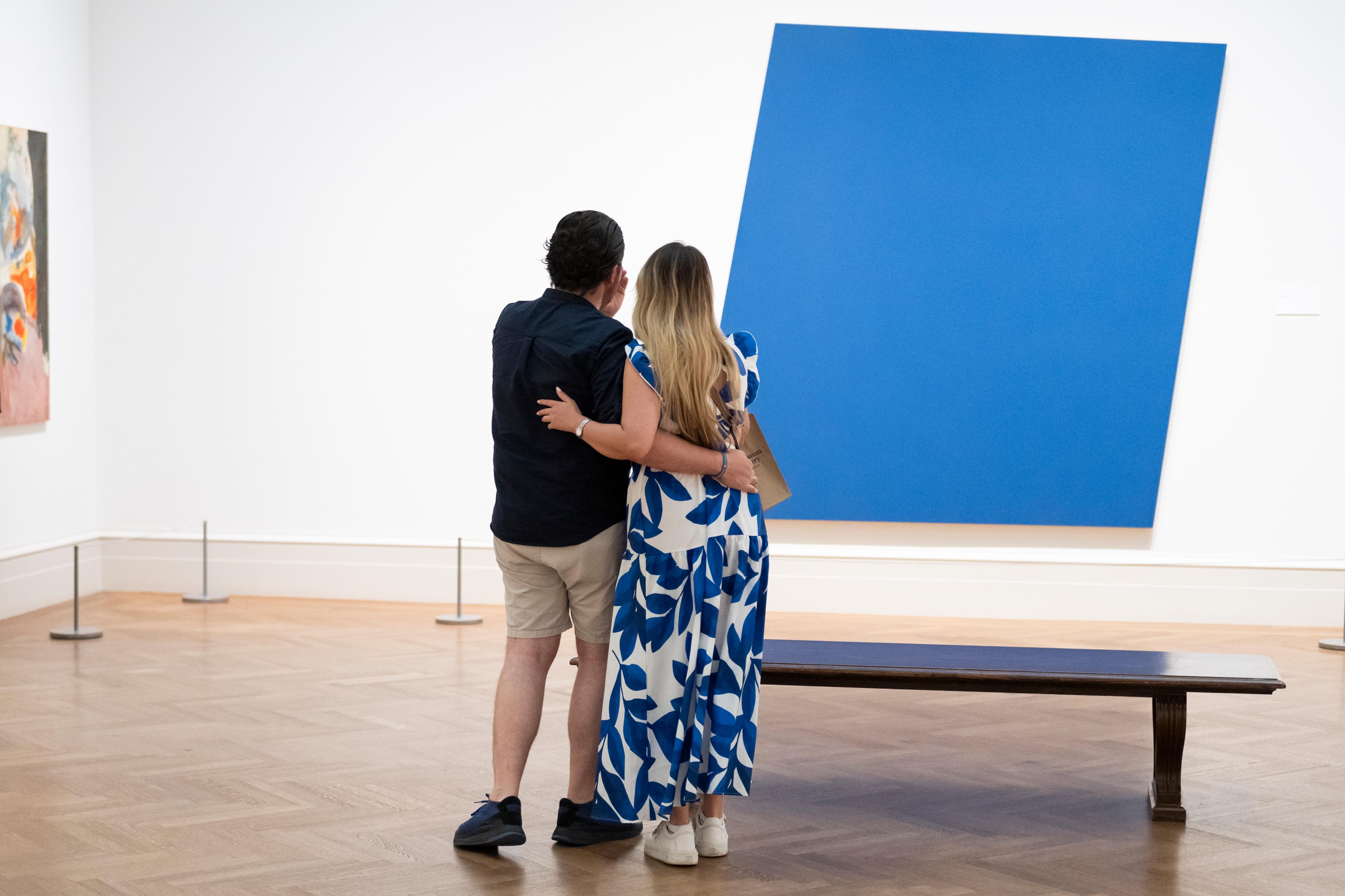 A couple poses in front of a bright blue work in The Met's Modern and Contemporary Wing.