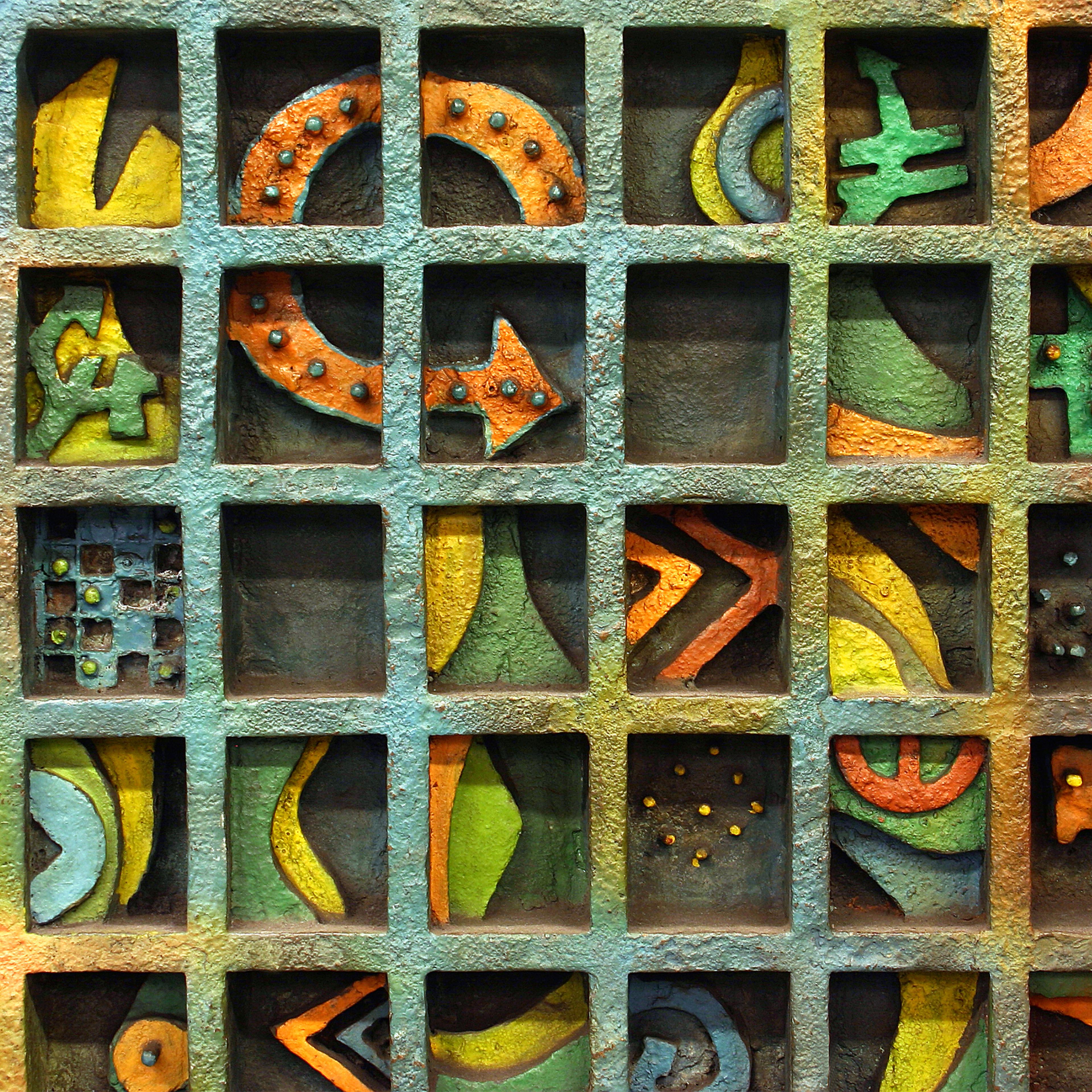 Detail image of metal square with multi figured object with a variety of colors like orange, yellow and green. 