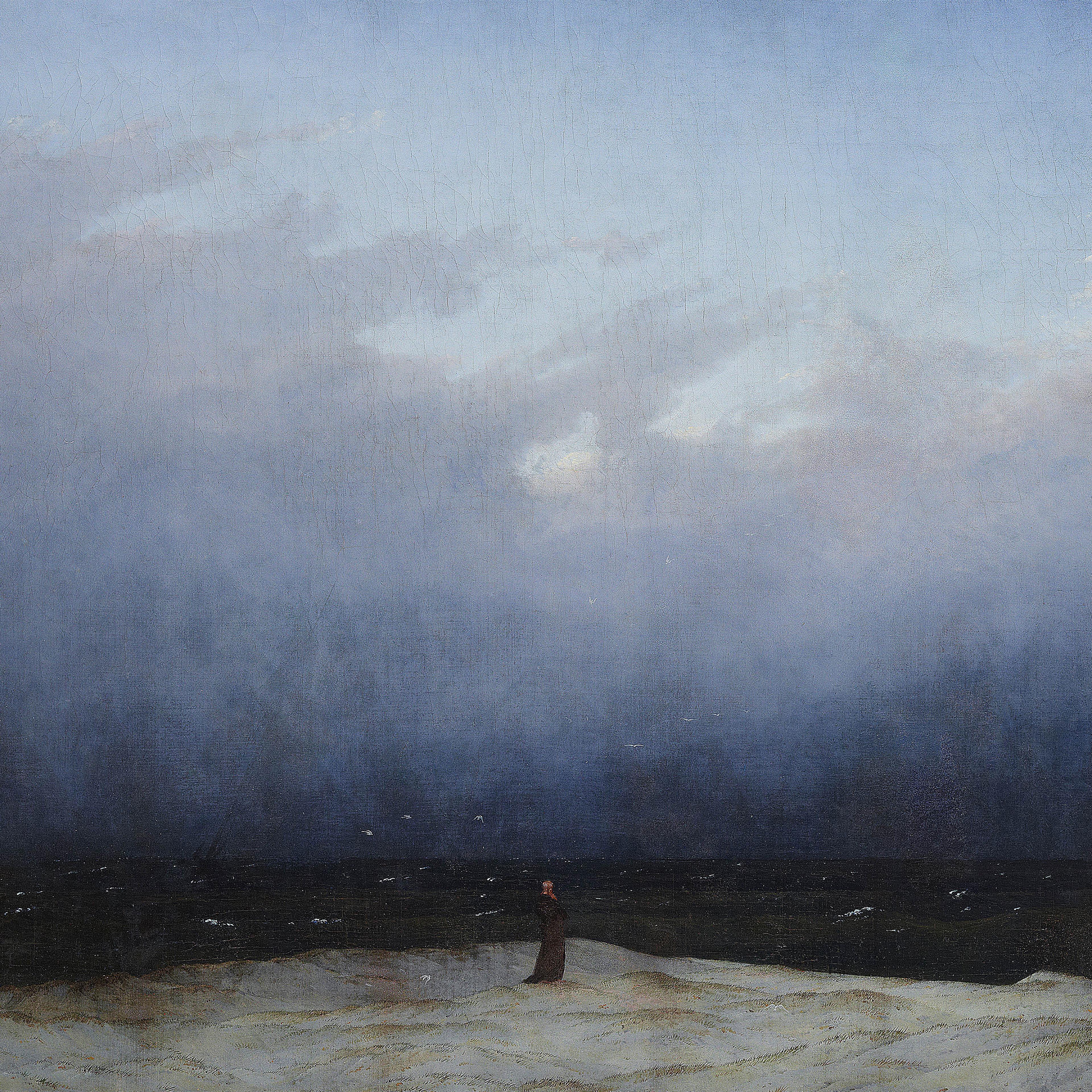 A solitary figure stands on a dune, gazing at the vast, dark sea under a cloudy sky.