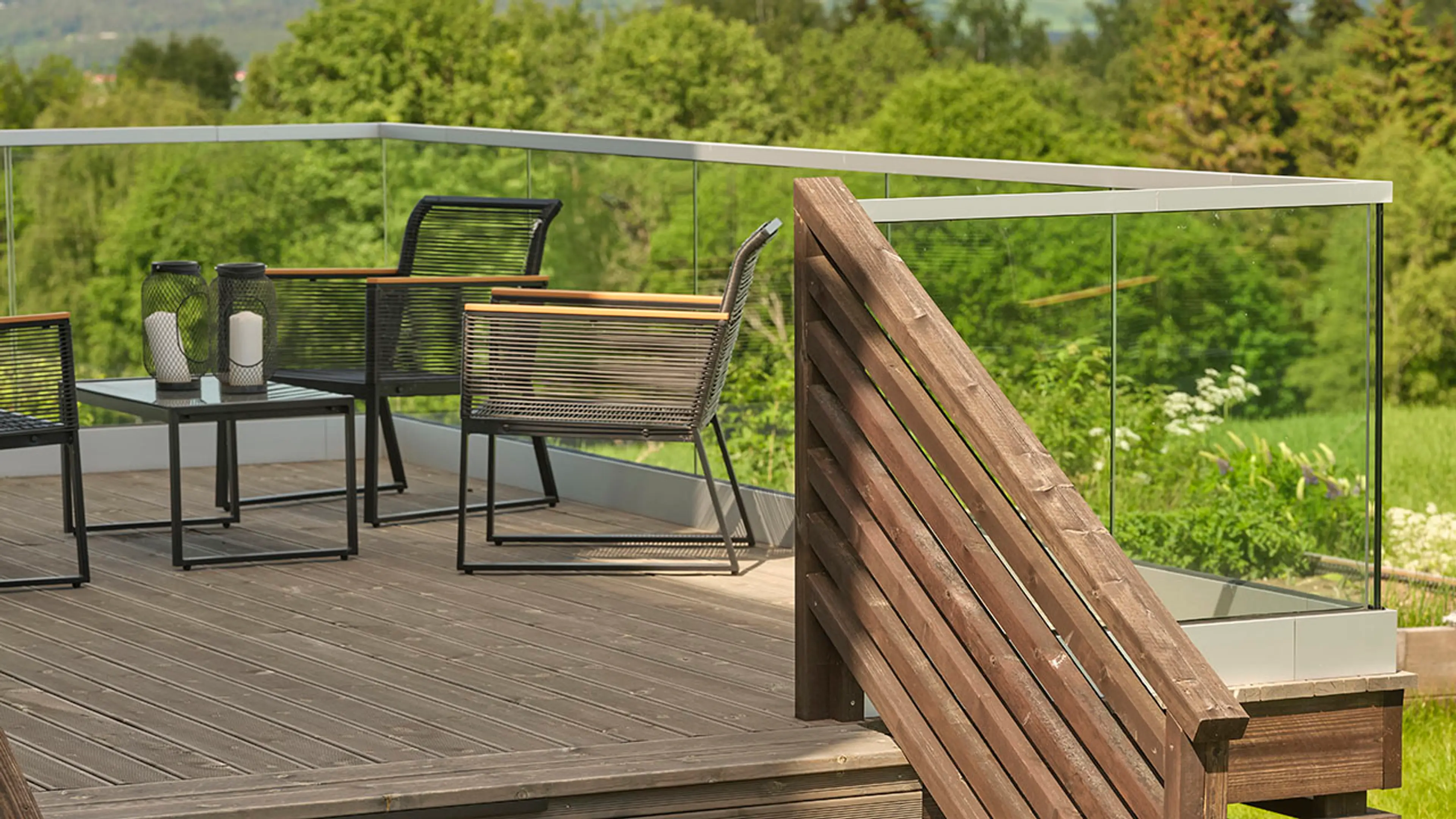 Terrasse med glassrekkverk og trapp med rekkverk av liggende lekter.