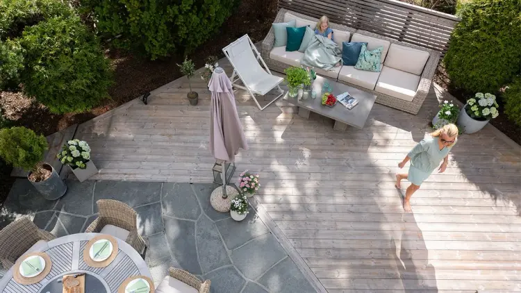 sommerlig kledd kvinne går barbeint over en terrasse