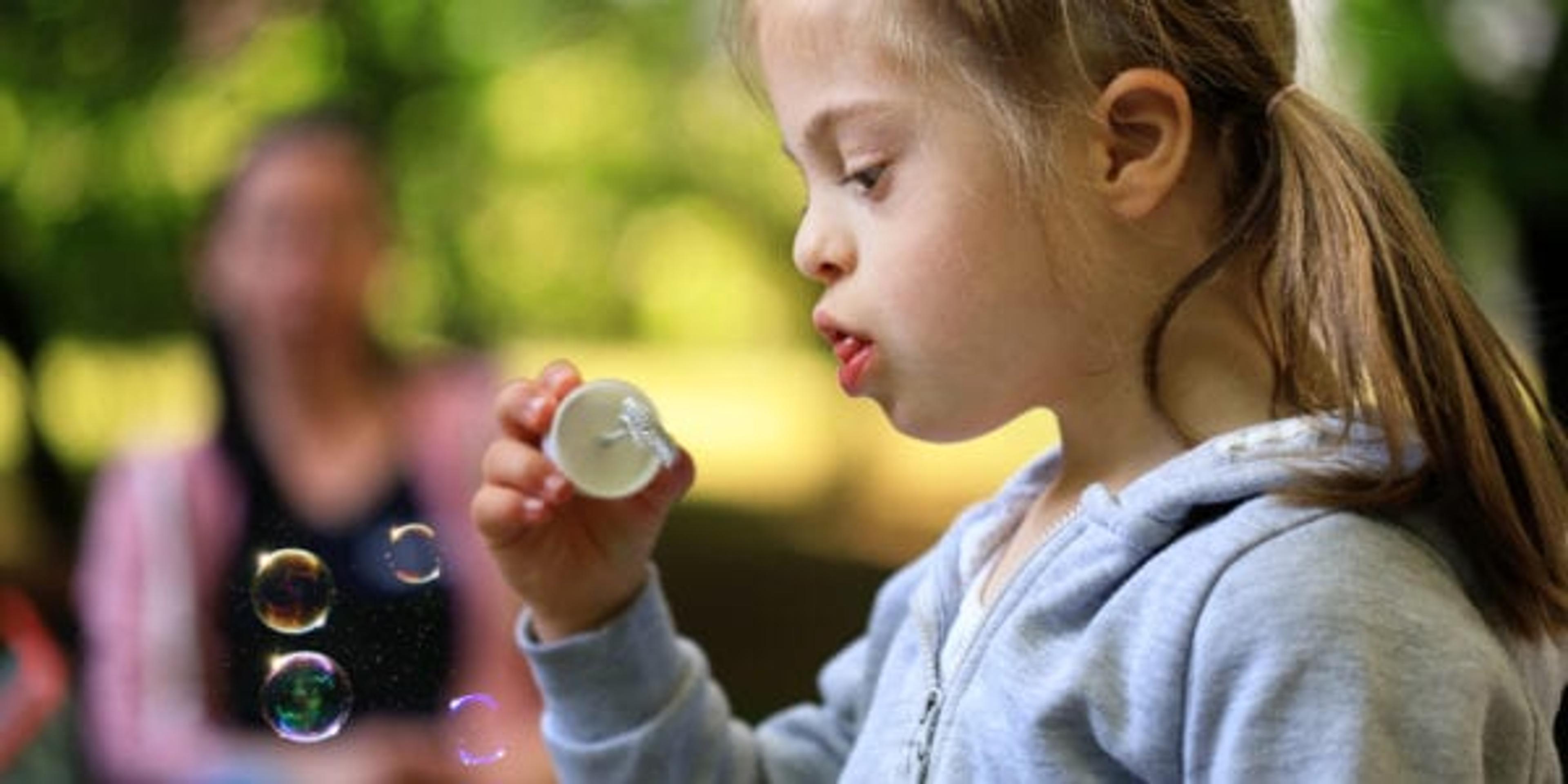 Little girl Having fun with the soap bubbles outdoors