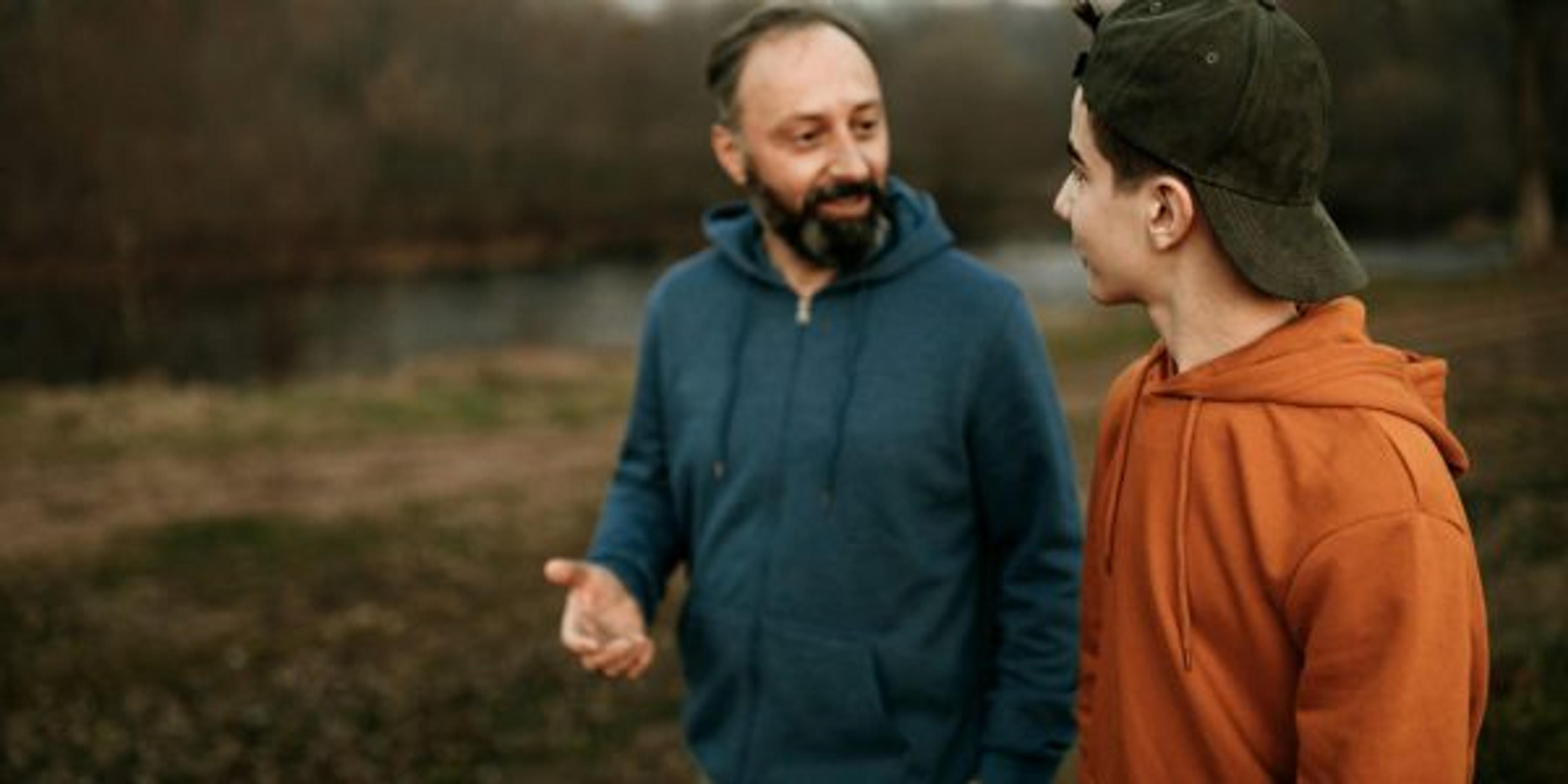 Man walks with his teenage son to talk about mental health